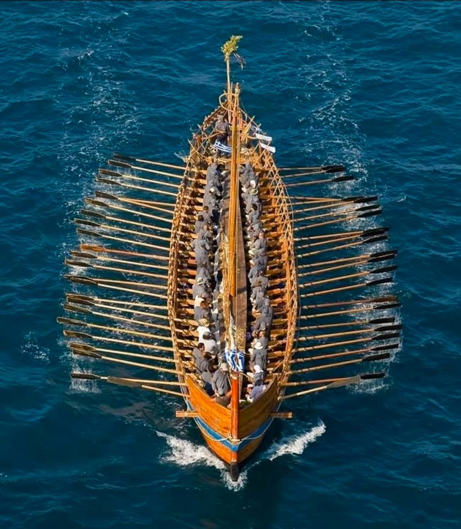 Aerial view of a rowed vessel, every oar pulling in unison.
